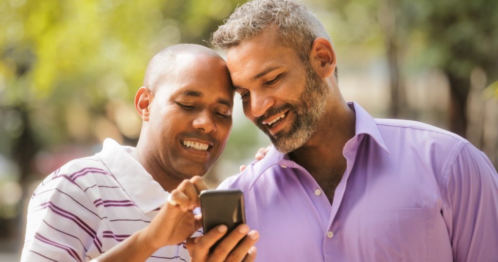 Happy Lgbt Gay Couple Looking At Pictures On Mobile Phone